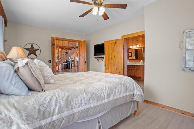 bedroom featuring light wood-type flooring, ceiling fan, baseboards, and connected bathroom
