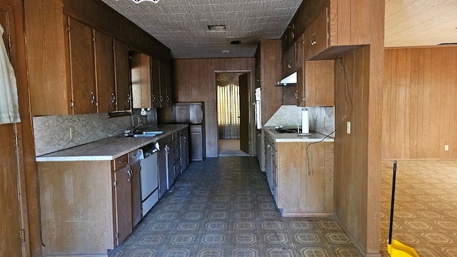 kitchen featuring stainless steel dishwasher, wood walls, backsplash, and range hood