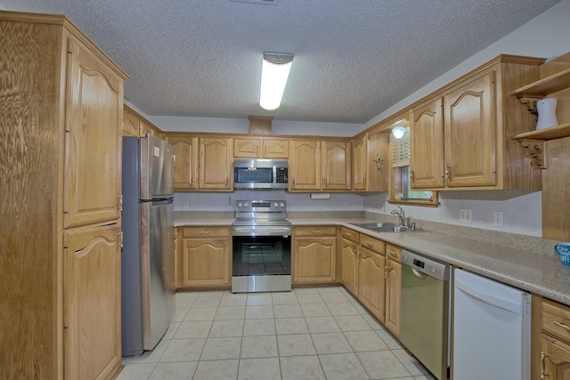 kitchen with a textured ceiling, sink, light tile patterned floors, and stainless steel appliances