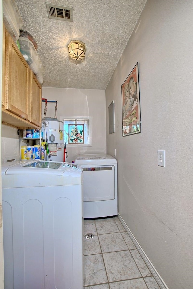 laundry area featuring cabinets, independent washer and dryer, a textured ceiling, and light tile patterned floors