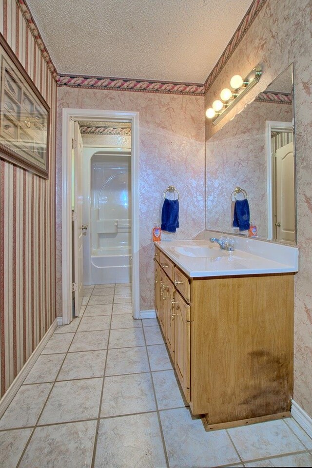 bathroom with tile patterned flooring, vanity, and a textured ceiling