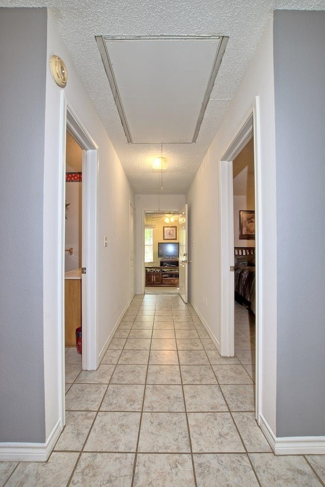 hallway with light tile patterned floors and a textured ceiling