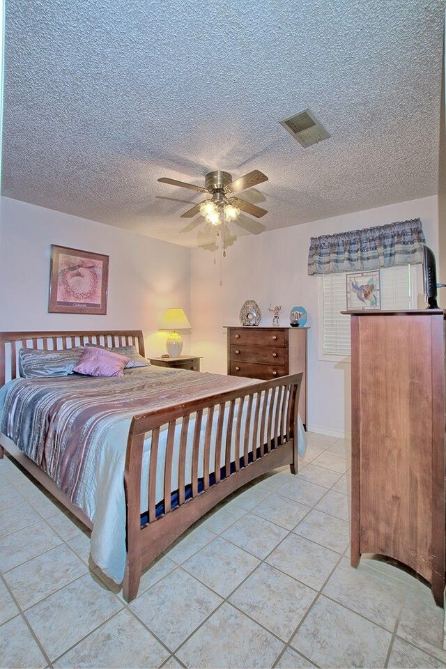 tiled bedroom with ceiling fan and a textured ceiling