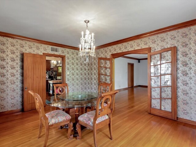 dining room featuring a chandelier, light wood-type flooring, and ornamental molding