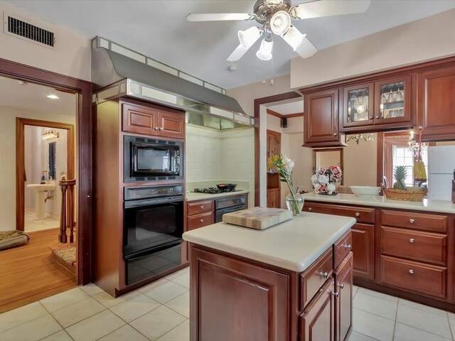 kitchen featuring a center island, black appliances, ceiling fan, light tile patterned floors, and tasteful backsplash