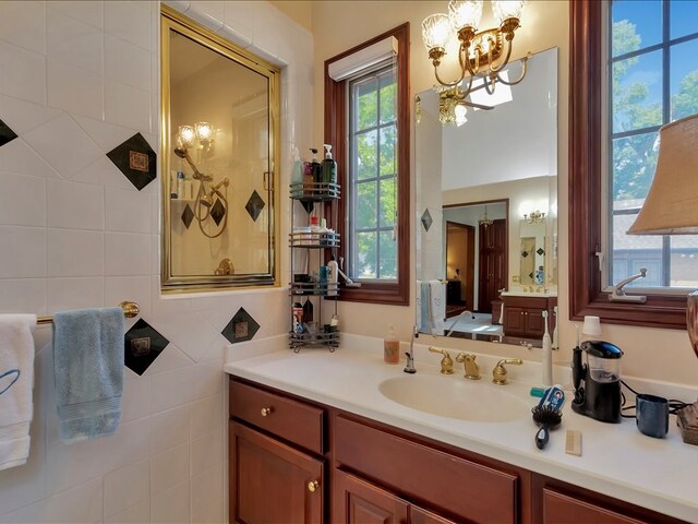 bathroom featuring vanity, an inviting chandelier, and tile walls