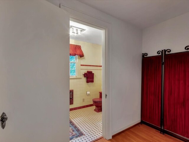 hallway featuring light hardwood / wood-style floors and tile walls