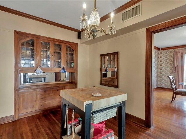 dining area featuring dark hardwood / wood-style flooring, ornamental molding, and a chandelier