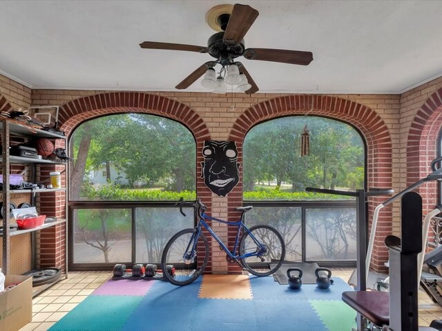 exercise area with ceiling fan and brick wall