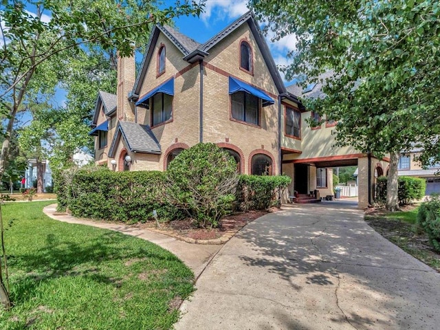 tudor home featuring a carport and a front yard