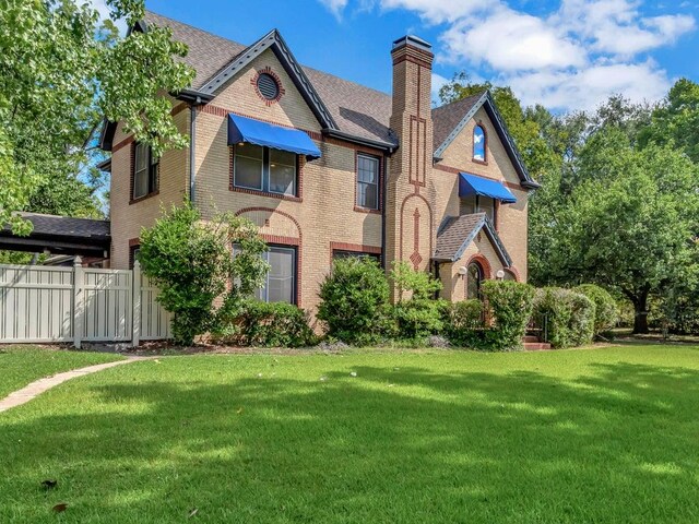 tudor home featuring a carport and a front yard