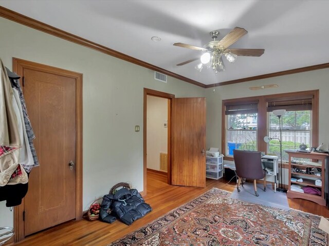 home office with light wood-type flooring, ceiling fan, and crown molding