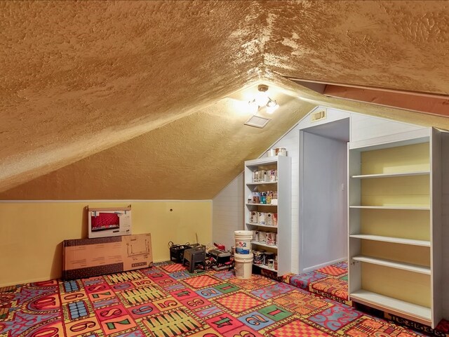 additional living space featuring lofted ceiling and a textured ceiling