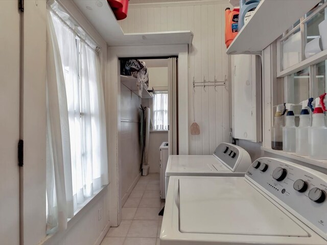 washroom with independent washer and dryer, plenty of natural light, wood walls, and light tile patterned flooring