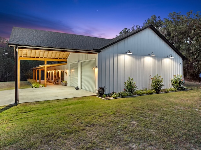 back house at dusk with a carport and a lawn