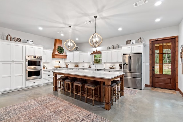 kitchen with appliances with stainless steel finishes, a kitchen breakfast bar, a center island, white cabinetry, and hanging light fixtures