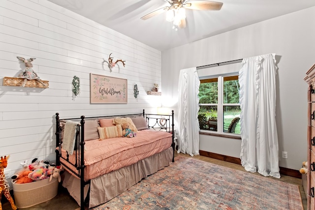 bedroom with ceiling fan and wooden walls