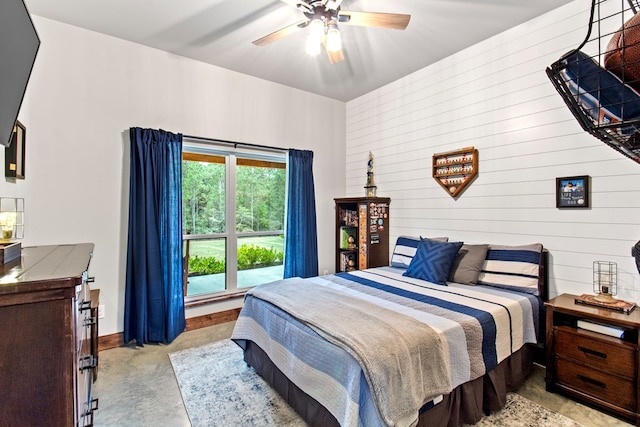 bedroom with ceiling fan and wood walls