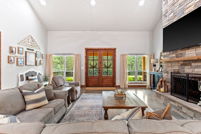 living room featuring hardwood / wood-style floors, a stone fireplace, high vaulted ceiling, and french doors