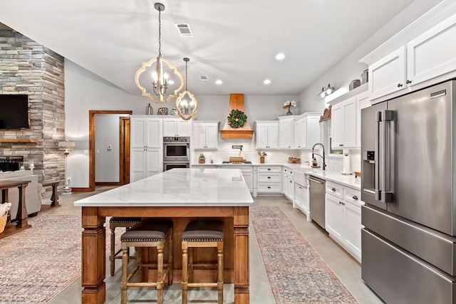 kitchen featuring premium range hood, decorative backsplash, appliances with stainless steel finishes, decorative light fixtures, and a kitchen island