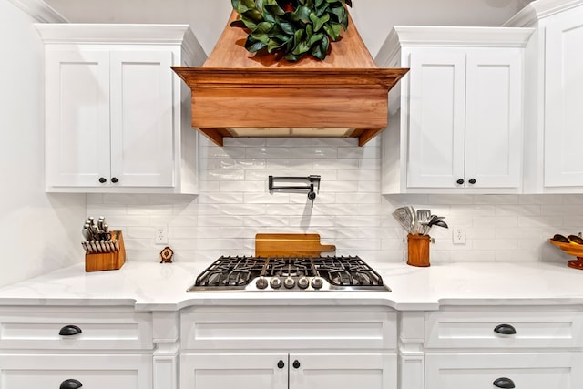 kitchen with light stone countertops, premium range hood, white cabinetry, and stainless steel gas cooktop