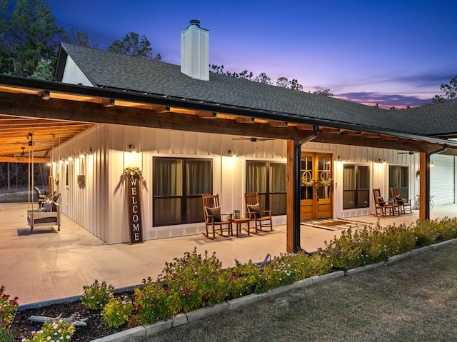 back house at dusk with ceiling fan and a patio area