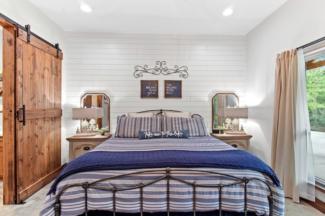 bedroom featuring light carpet, a barn door, and wood walls