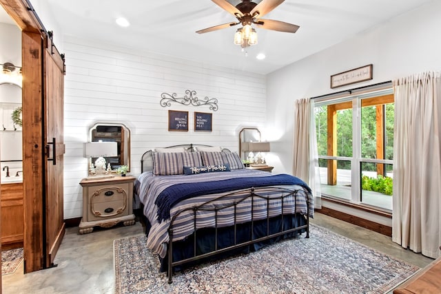 bedroom featuring concrete flooring, a barn door, ceiling fan, and wooden walls