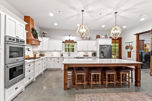 kitchen with a breakfast bar, appliances with stainless steel finishes, decorative light fixtures, a kitchen island, and white cabinetry