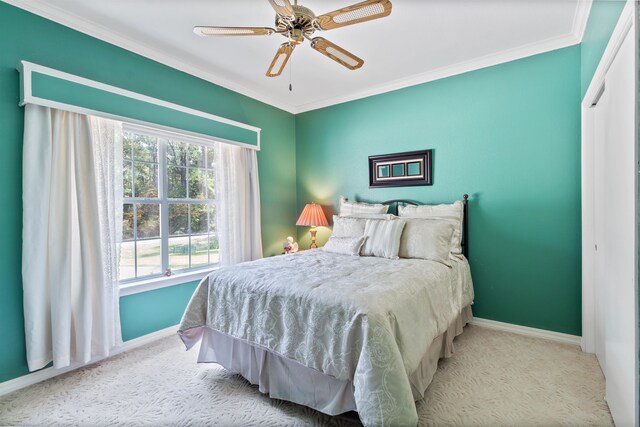 bedroom with ceiling fan, crown molding, light carpet, and a closet