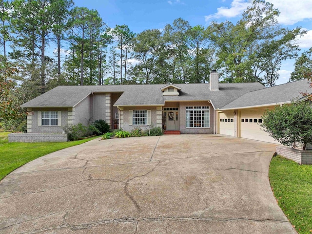 827 Duffer Dr, Brookeland, TX 75931 - view of front of home featuring concrete driveway, a chimney, brick siding, a garage, and a front lawn