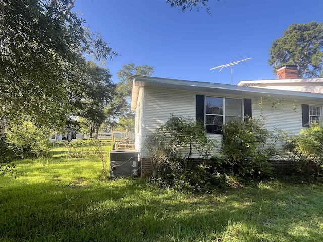 view of side of home with a lawn and central AC unit