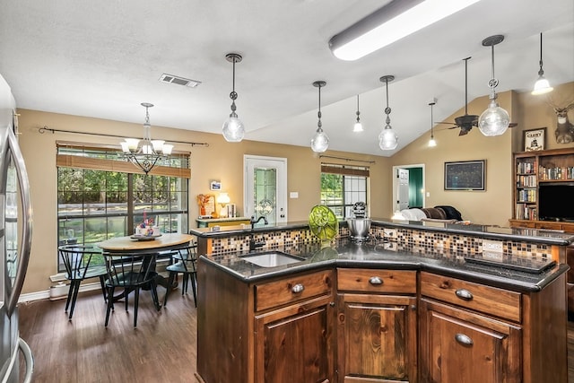 kitchen with dark hardwood / wood-style flooring, a notable chandelier, stainless steel refrigerator, hanging light fixtures, and lofted ceiling