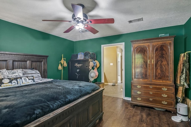 bedroom with ceiling fan, dark wood-type flooring, and a textured ceiling