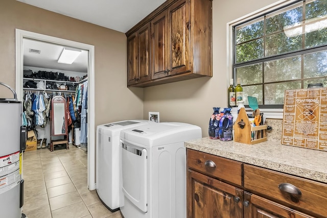 clothes washing area featuring cabinets, independent washer and dryer, light tile patterned flooring, and water heater