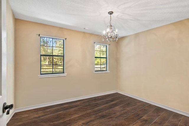 spare room with a notable chandelier, dark hardwood / wood-style flooring, and a textured ceiling