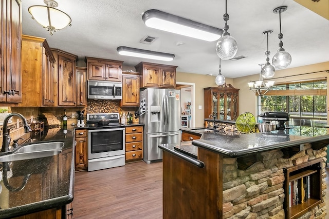 kitchen featuring appliances with stainless steel finishes, sink, decorative light fixtures, a center island, and a breakfast bar area