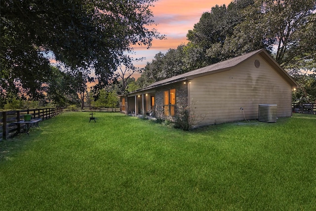 property exterior at dusk with a yard and central AC