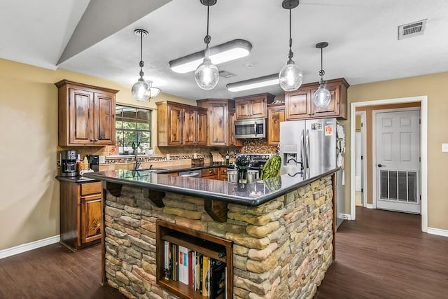 kitchen featuring dark hardwood / wood-style flooring, tasteful backsplash, stainless steel appliances, a kitchen island with sink, and pendant lighting