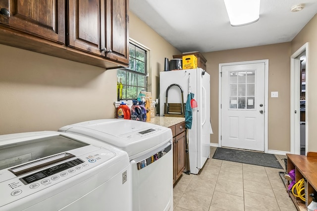 clothes washing area featuring light tile patterned floors, cabinets, and independent washer and dryer