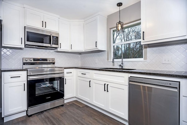 kitchen featuring white cabinetry, stainless steel appliances, dark wood-type flooring, and a sink