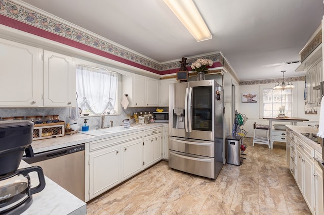 kitchen with sink, decorative light fixtures, appliances with stainless steel finishes, a notable chandelier, and white cabinetry