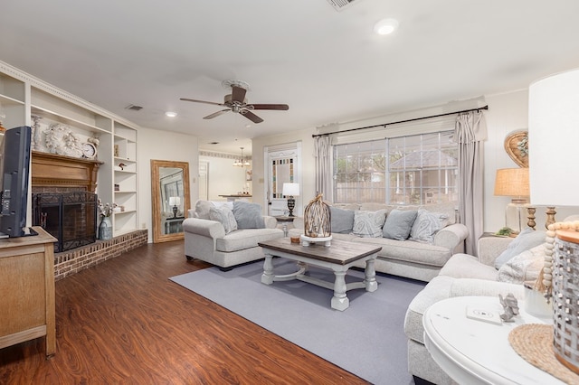 living room with a fireplace, ceiling fan, built in features, and dark hardwood / wood-style floors