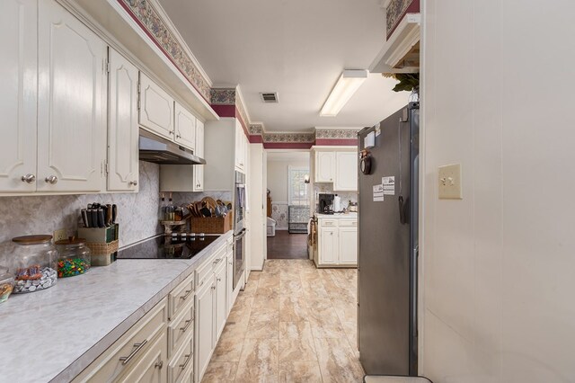 kitchen featuring decorative backsplash, stainless steel appliances, white cabinetry, and light hardwood / wood-style floors