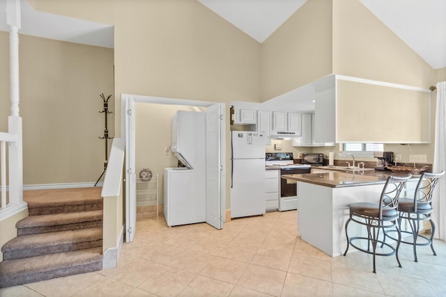 kitchen featuring kitchen peninsula, a breakfast bar, white appliances, sink, and white cabinets