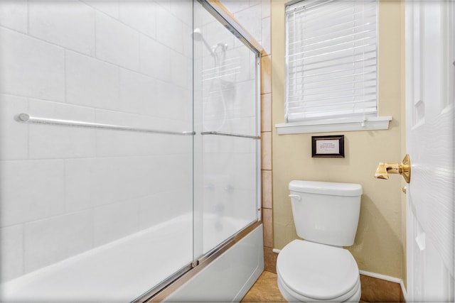 bathroom featuring shower / bath combination with glass door, tile patterned flooring, and toilet