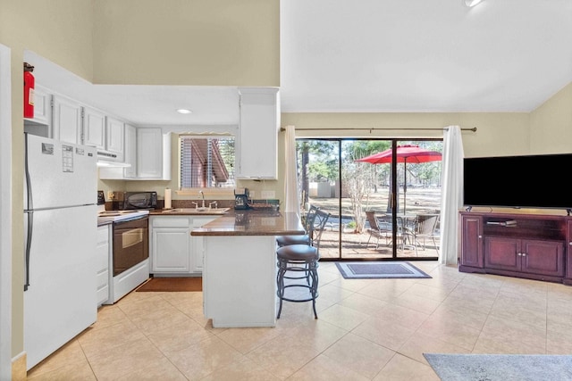 kitchen featuring a breakfast bar, white appliances, exhaust hood, white cabinets, and light tile patterned floors