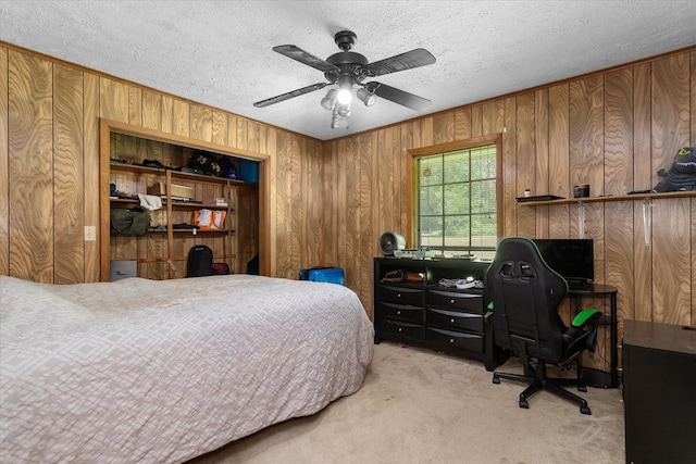 carpeted bedroom featuring a textured ceiling, ceiling fan, and wood walls