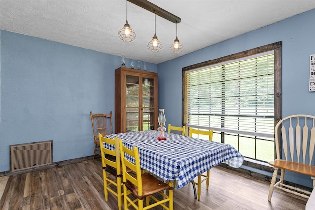 dining room featuring a textured ceiling and dark hardwood / wood-style floors