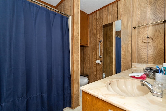 bathroom with a textured ceiling, vanity, toilet, and wooden walls